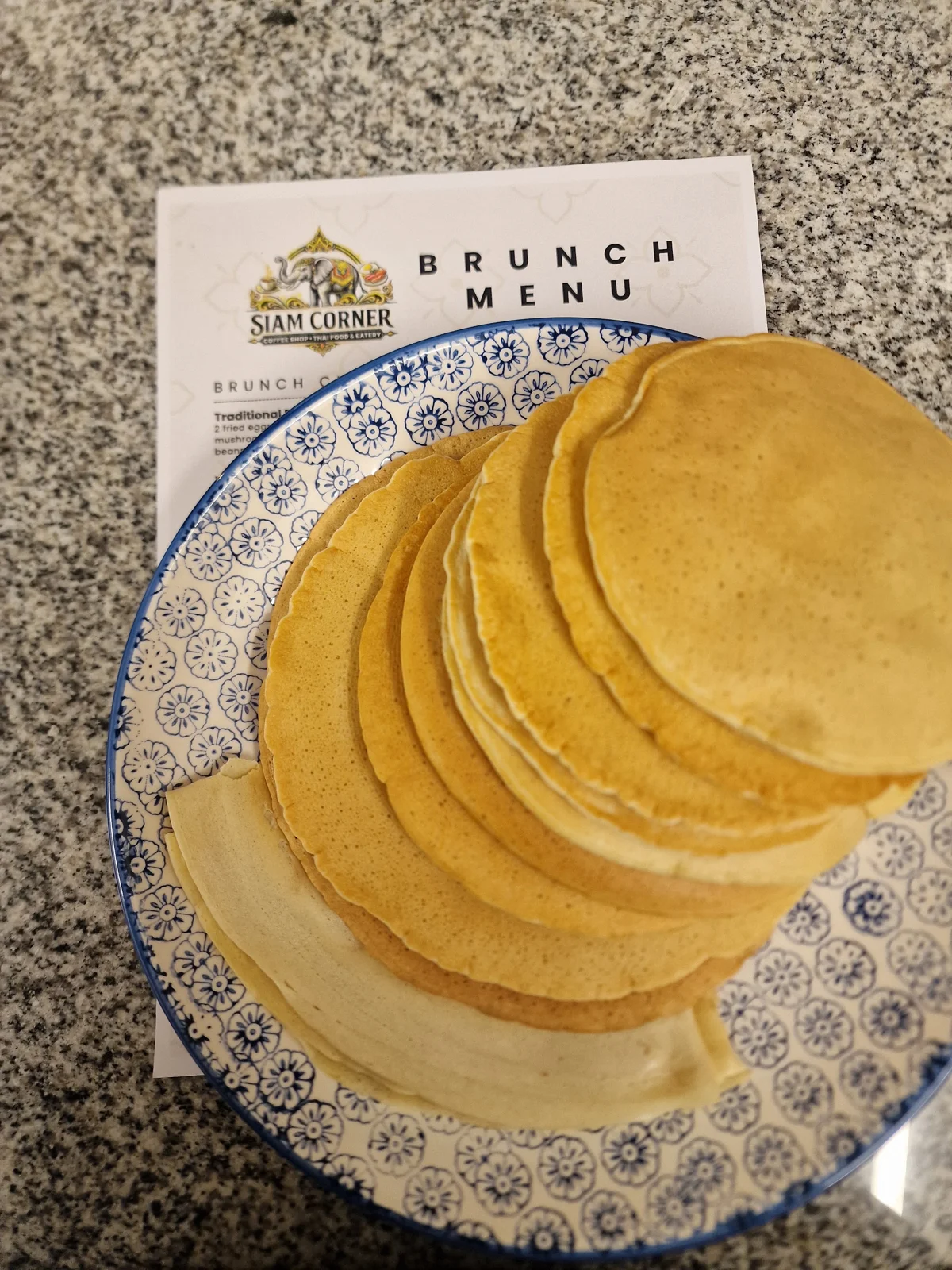 A stack of pancakes beside Siam Corner's brunch menu